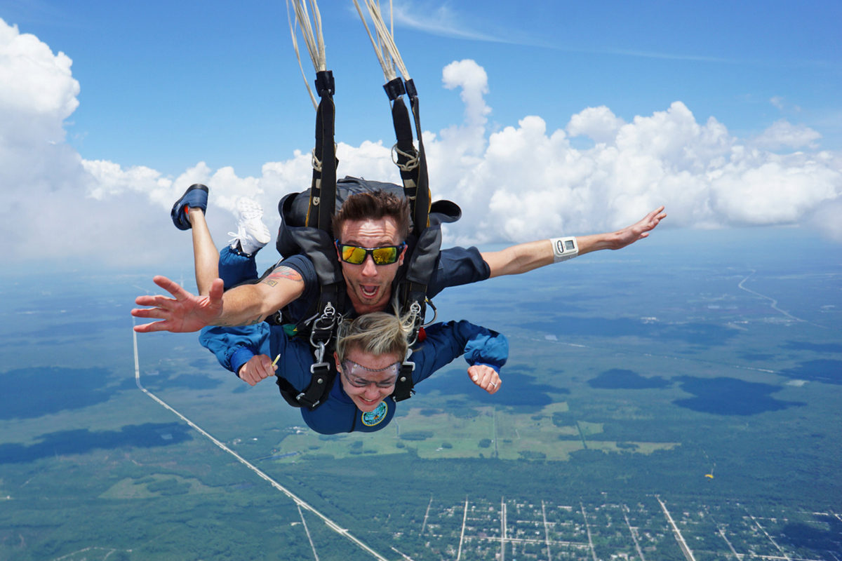 young woman and tandem skydiving instructor fly through crystal blue FL skies near Orlando