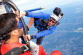 tandem skydiver making first skydive sits on the edge of plane with instructor before making the leap